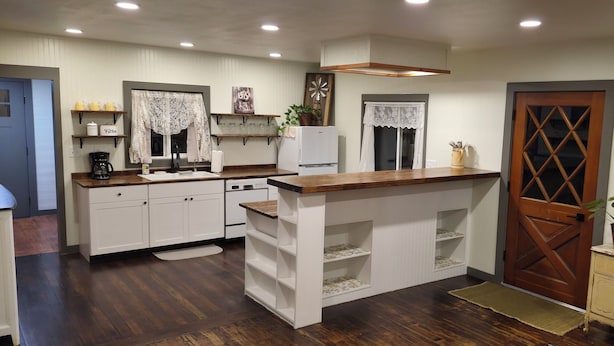 A compact kitchen with white cabinetry, a wooden countertop, and a built-in shelf.