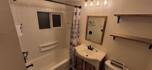 Un bany amb banyera, finestra, rentatòri i mirall.