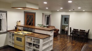 A compact kitchen with a stove, sink, and wooden counter. There is a dining area with chairs and a table.