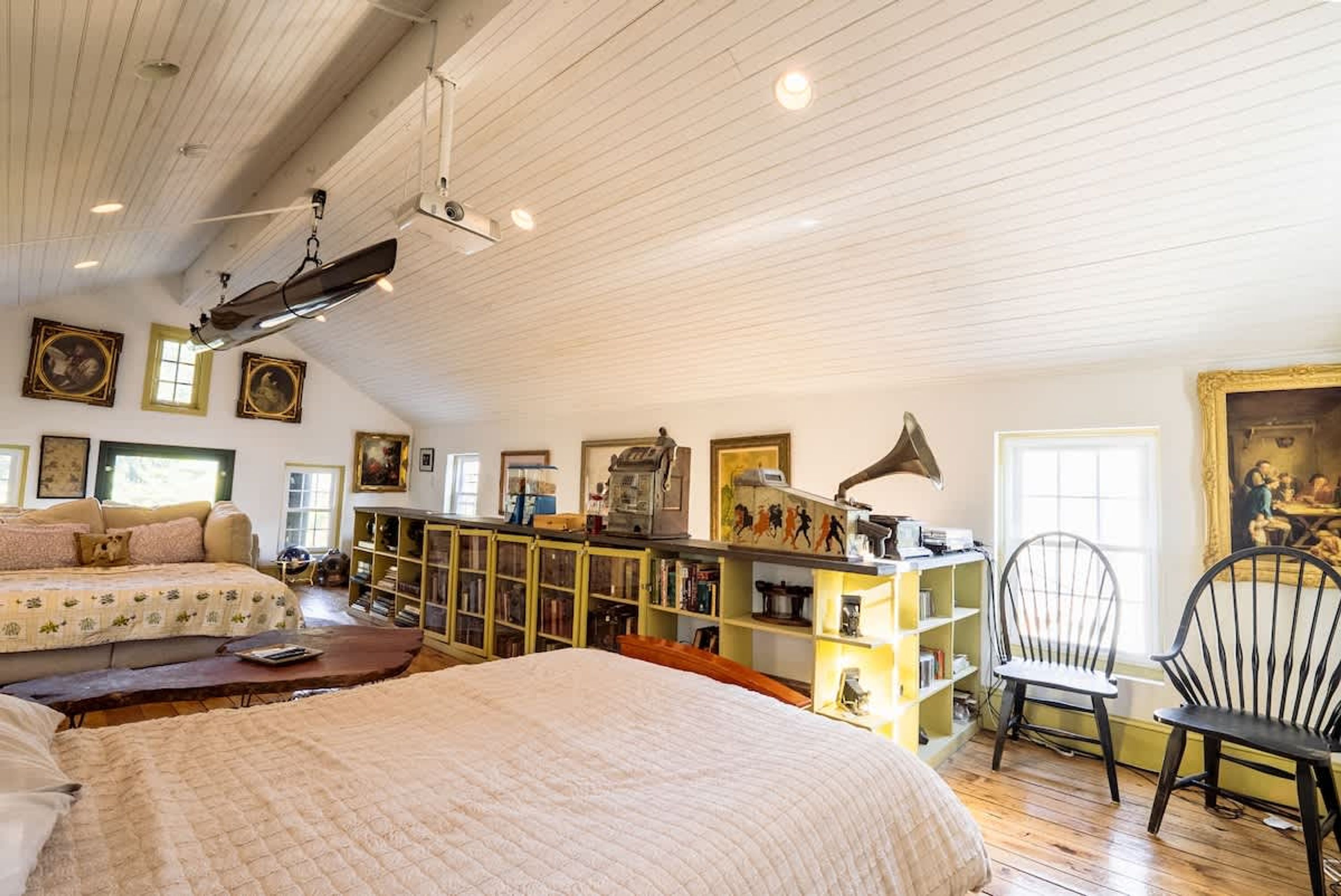 A room with a bed, a desk with a lamp, a chair, and shelves with books and decorative items.