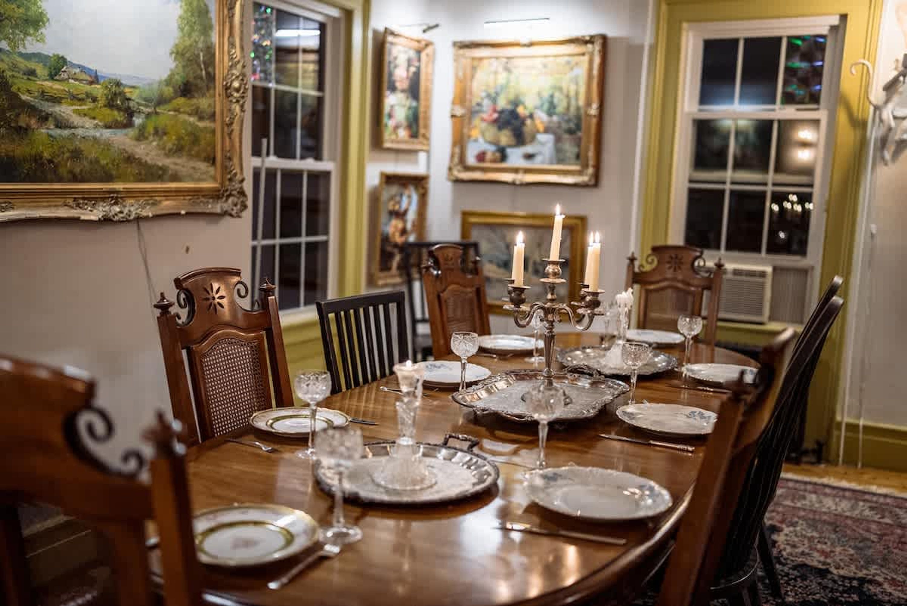 A dining room with a long wooden table set for a meal, surrounded by chairs.