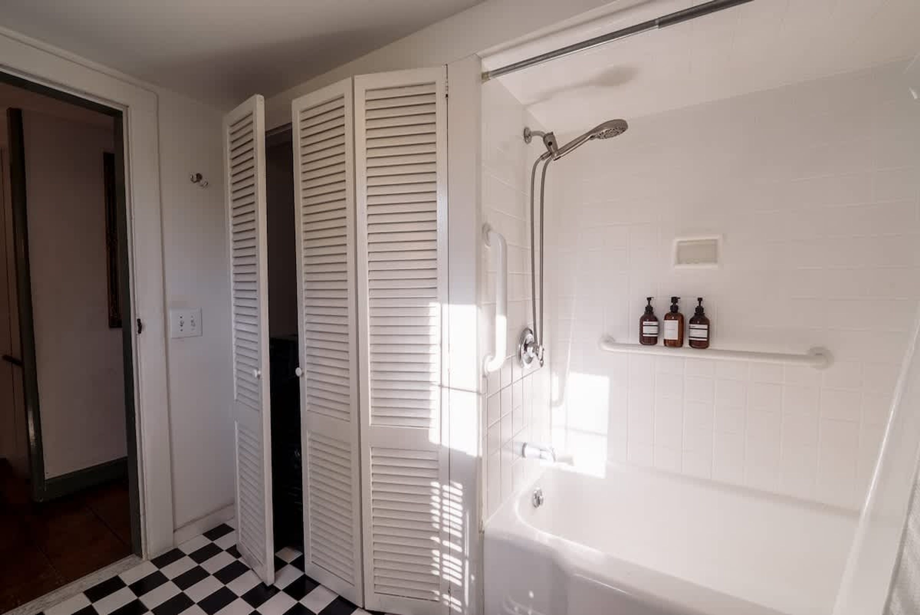 Een badkamer met een badkuip, douche en een plank met flessen.