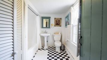 Un baño con un lavabo blanco, inodoro y suelo a cuadros.