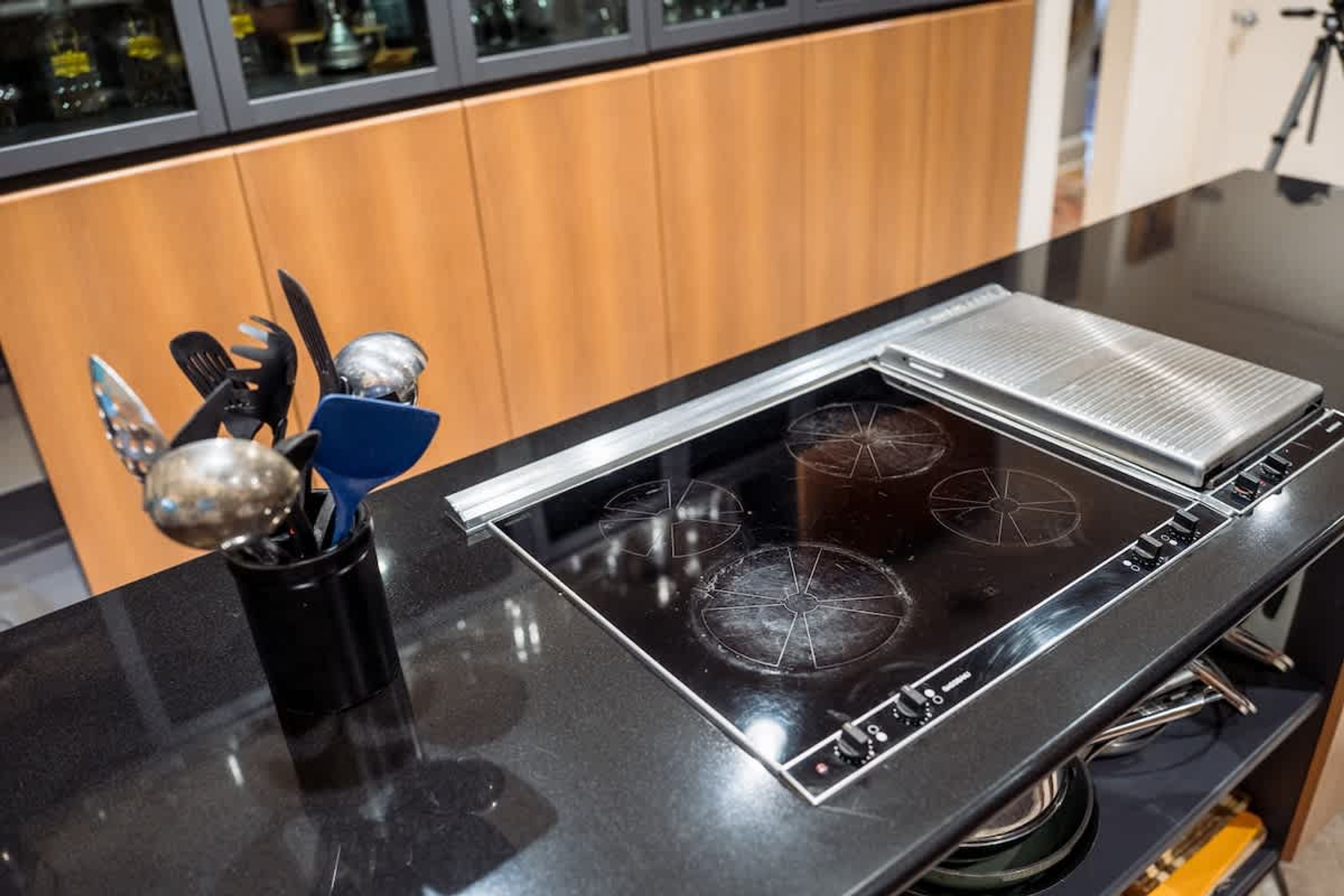 A kitchen with a black countertop, a built-in stove, and a coffee maker.