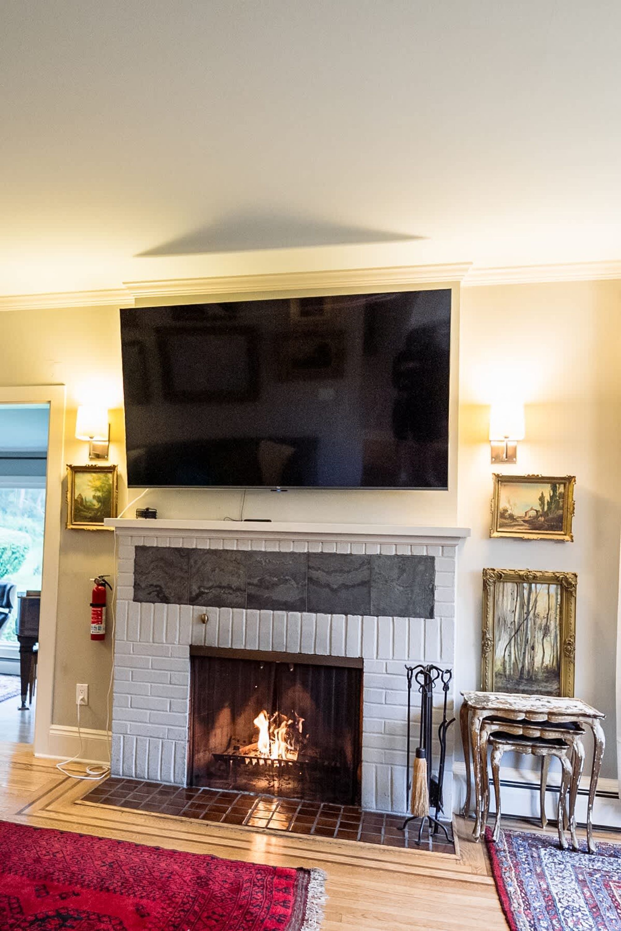 Una sala de estar con chimenea, un televisor de pantalla plana montado encima y una alfombra roja en el suelo.