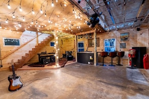 Un intérieur rustique en bois, avec un escalier, un coin bar et une guitare.
