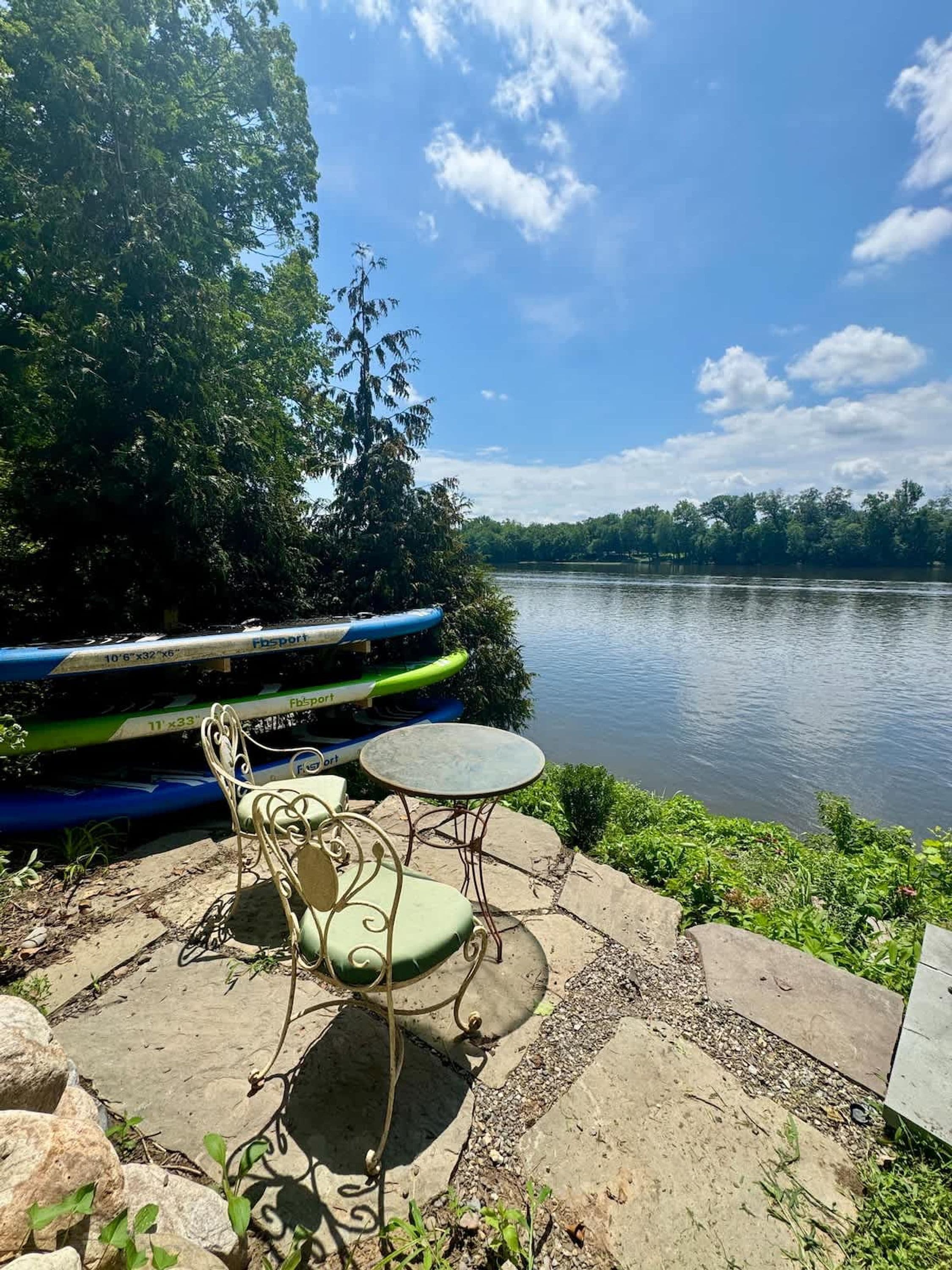 A lakeside patio with a table and chairs, a kayak, and a view of the lake.