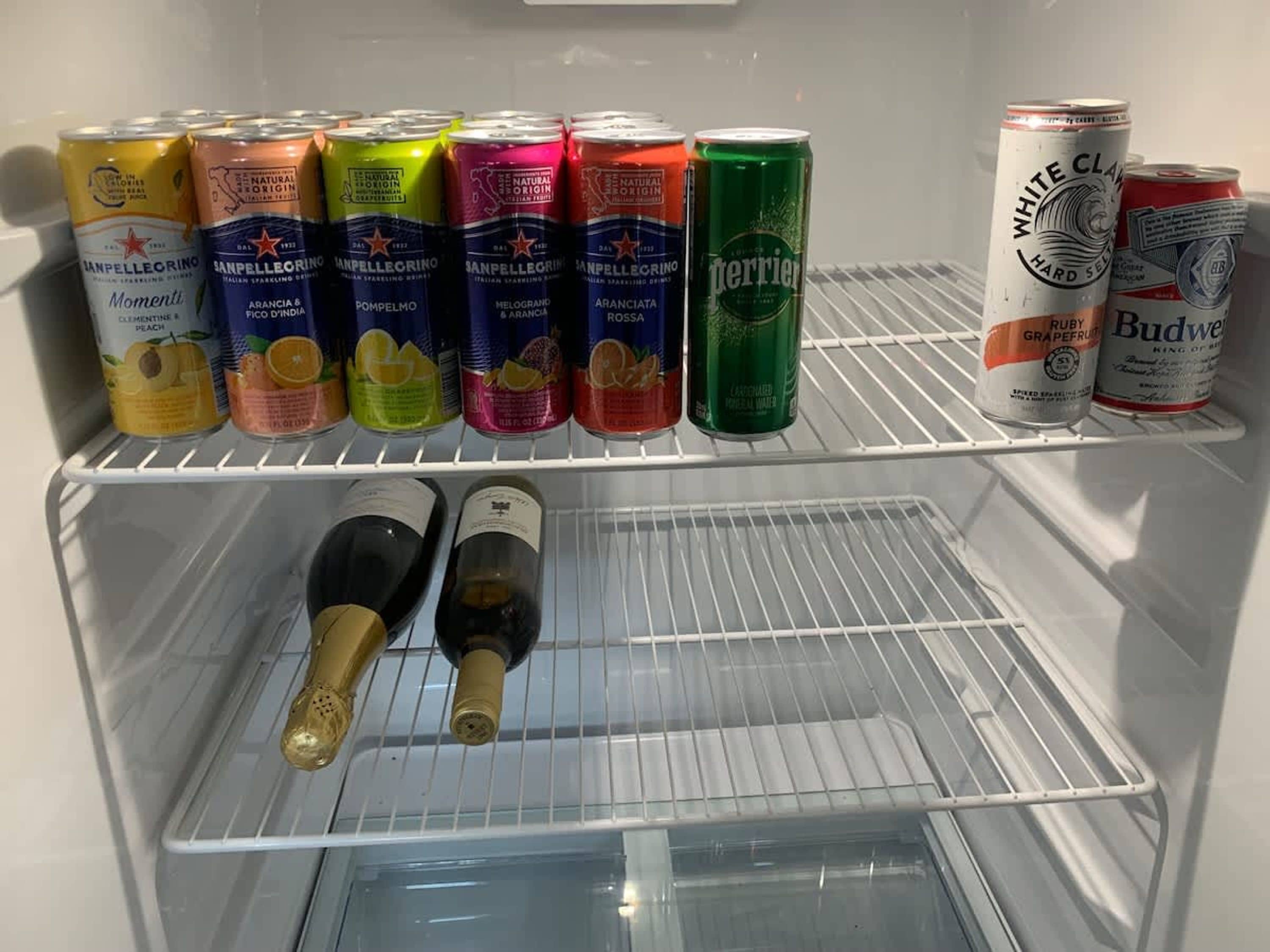 A refrigerator with various beverages including San Pellegrino sparkling water, Perrier, and Budweiser.