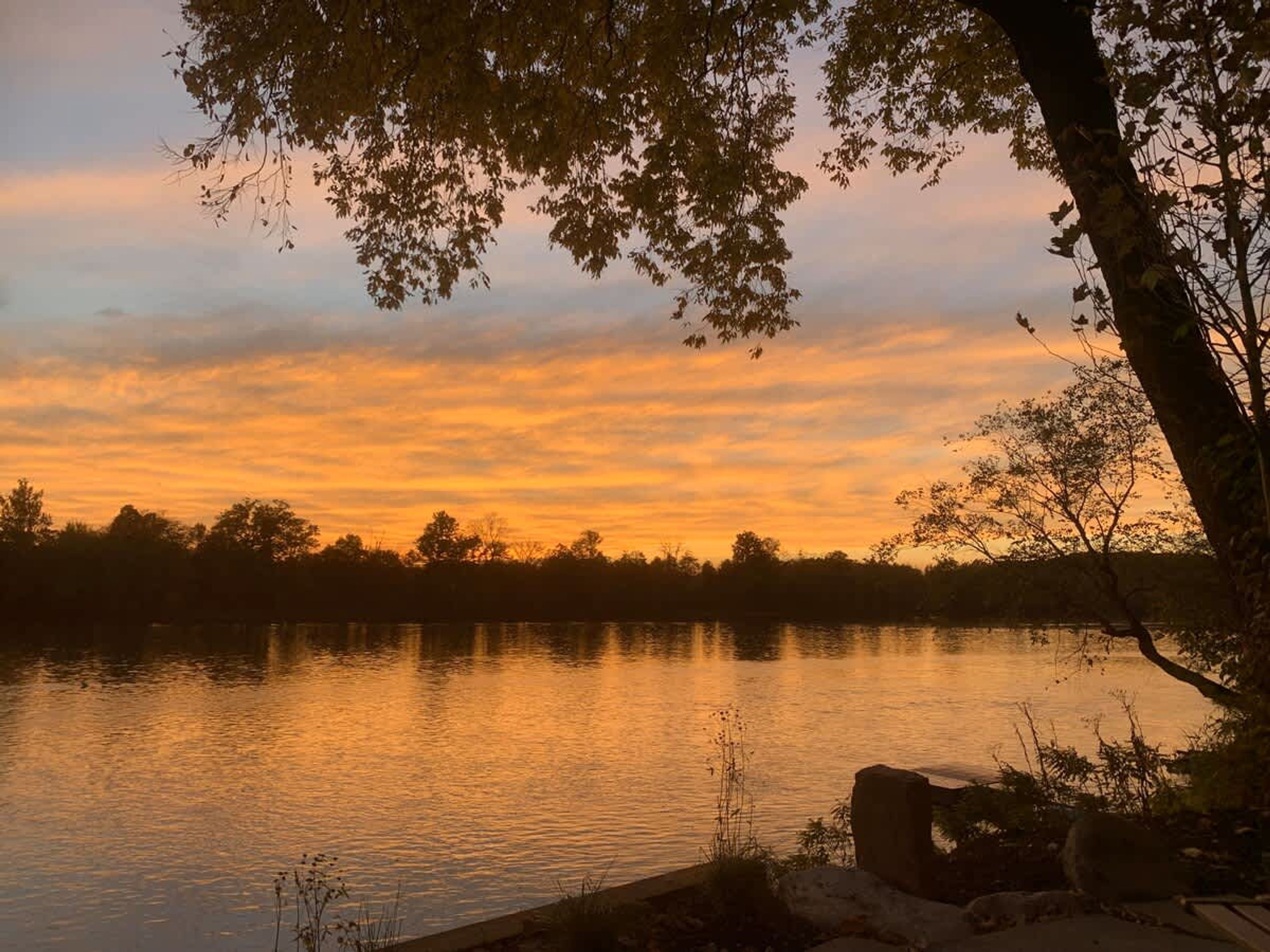 Ein friedlicher See im Abendlicht, die ruhige Wasseroberfläche spiegelt den Himmel wider.