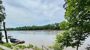 Een voetpad langs de rivier met een betonnen bank, een klein tafeltje en een steiger.