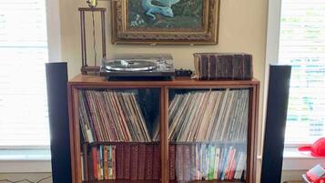 Ein Zimmer mit einer Holzbücherwand, voll mit Büchern und Schallplatten, einem gerahmten Gemälde einer blauen Füchsin an der Wand und einem Vintage-Radio obenauf.