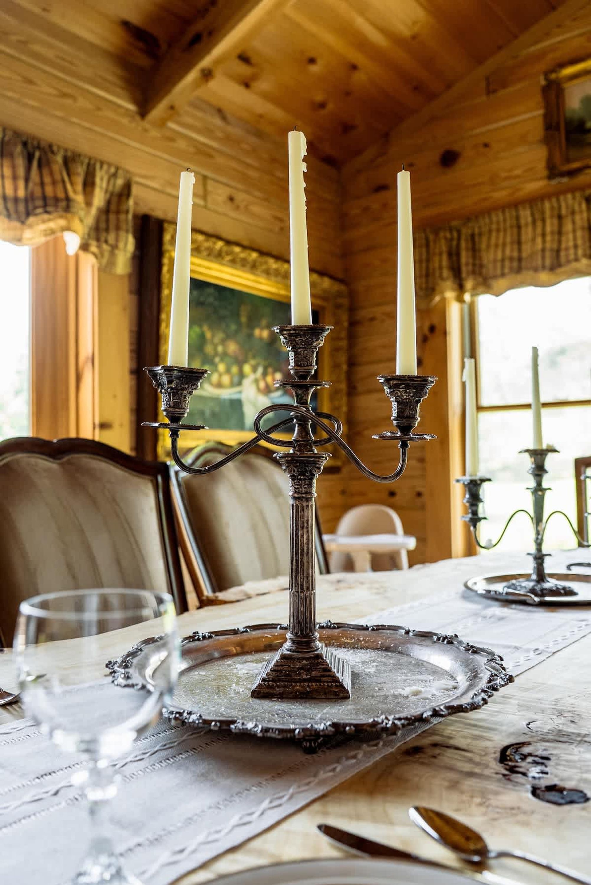 A wooden interior with a table set for dining, featuring a candle holder with three candles.