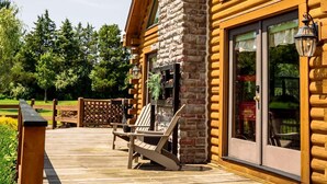 A log cabin with a stone chimney, large windows, and a wooden deck with outdoor seating. - Private Luxury Log Cabin (New Hope)