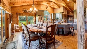 A spacious wooden dining area with a large table and chairs, a chandelier, and a view of the outdoors. - Private Luxury Log Cabin (New Hope)