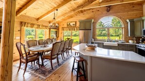 A wooden cabin interior with a dining area, kitchen, and large windows. - Private Luxury Log Cabin (New Hope)