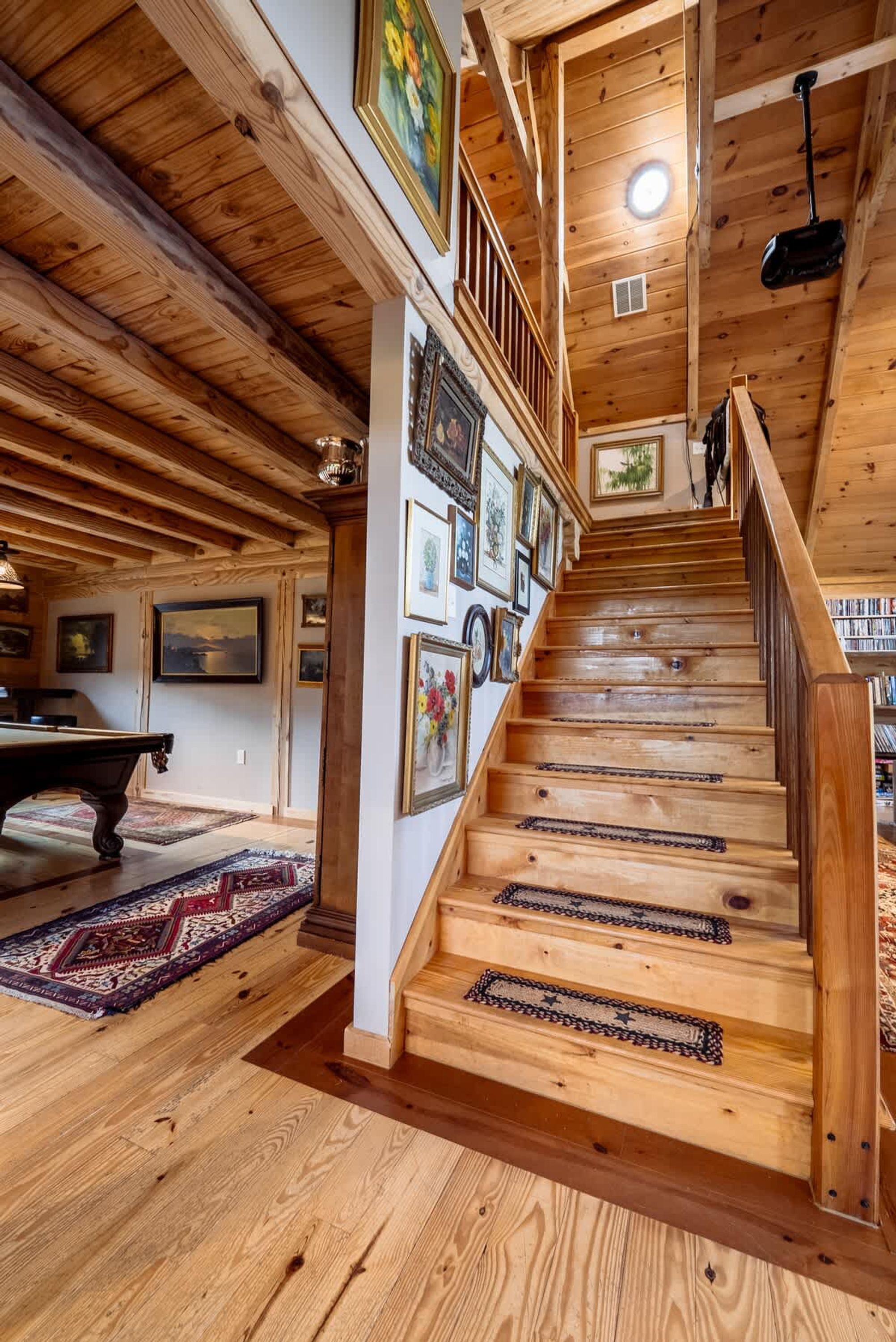 A wooden staircase with a handrail, leading to a second-floor area with a ceiling fan and a light fixture.