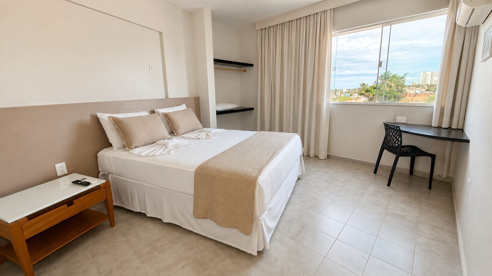 A hotel room with a bed, a desk, and a chair.