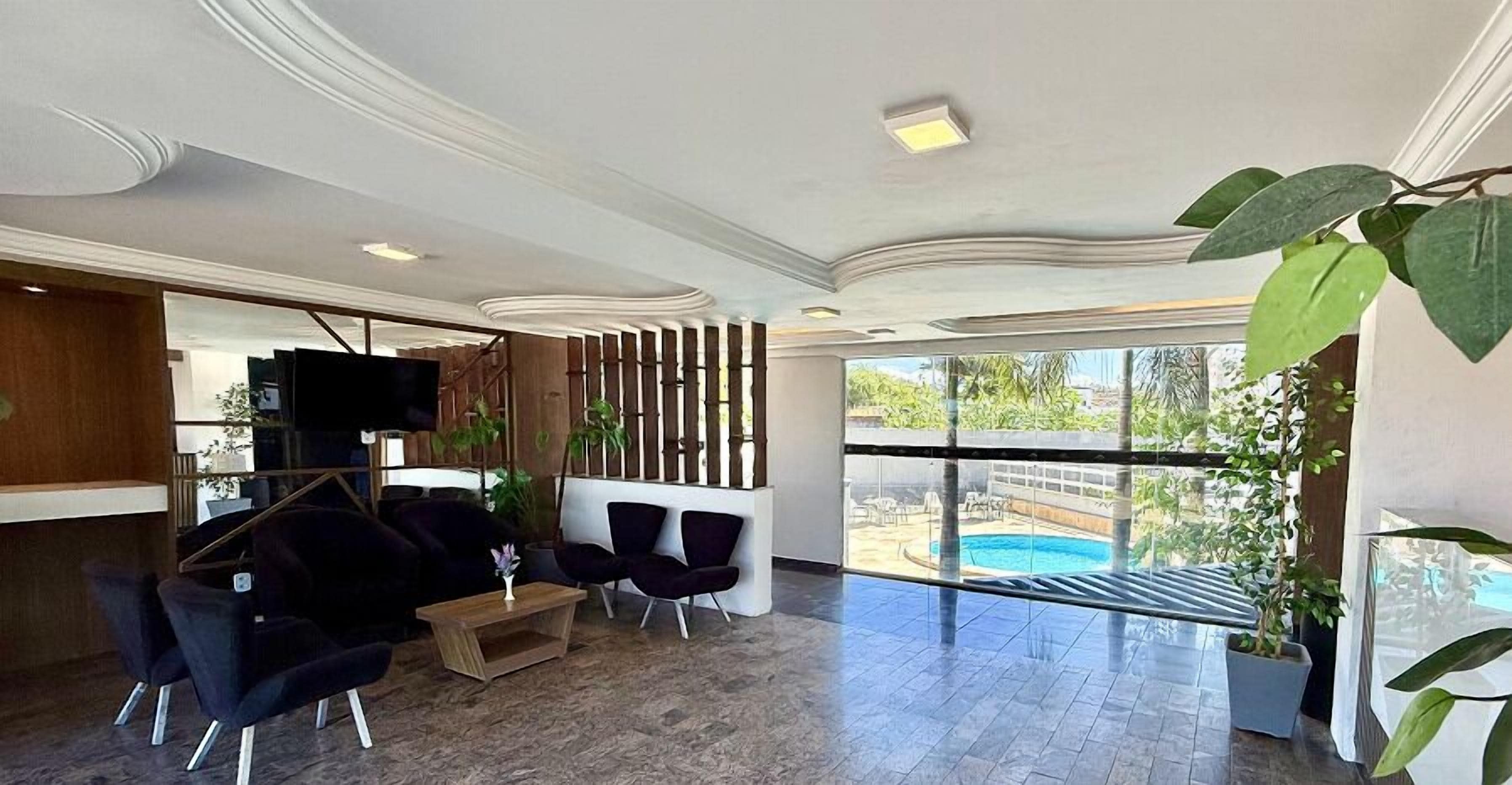 A modern lobby with a pool view, dark furniture, and a TV.
