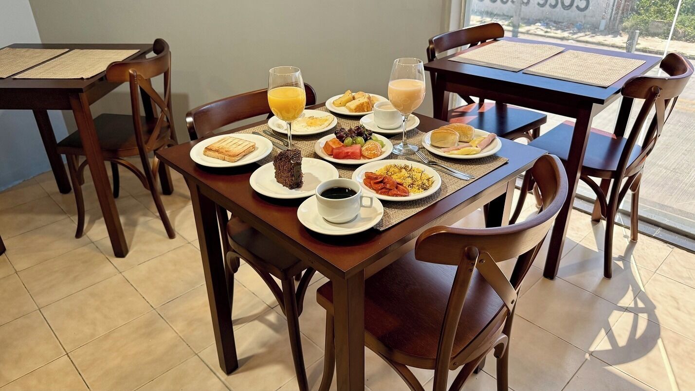 A breakfast table with various dishes, a glass of orange juice, and a cup of coffee.