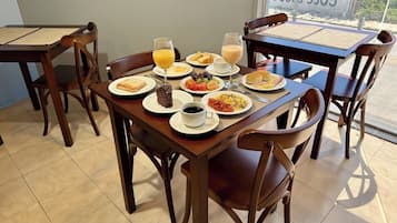 A breakfast table with various dishes, a glass of orange juice, and a cup of coffee.