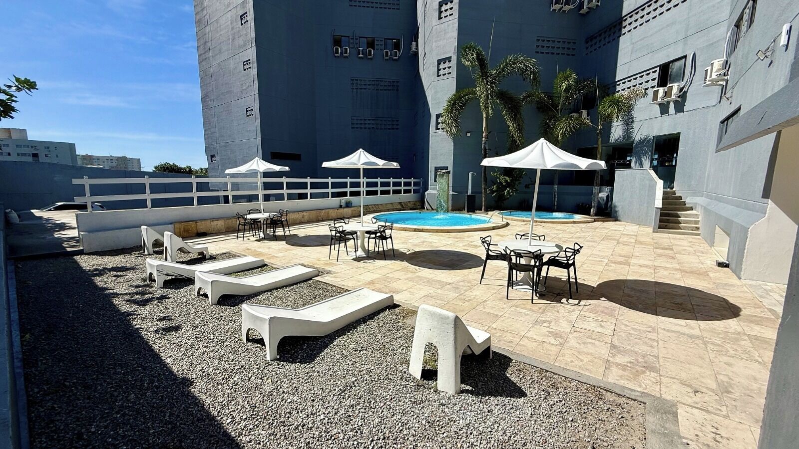 Una terraza en la azotea con sillones de descanso, piscina y mobiliario exterior.