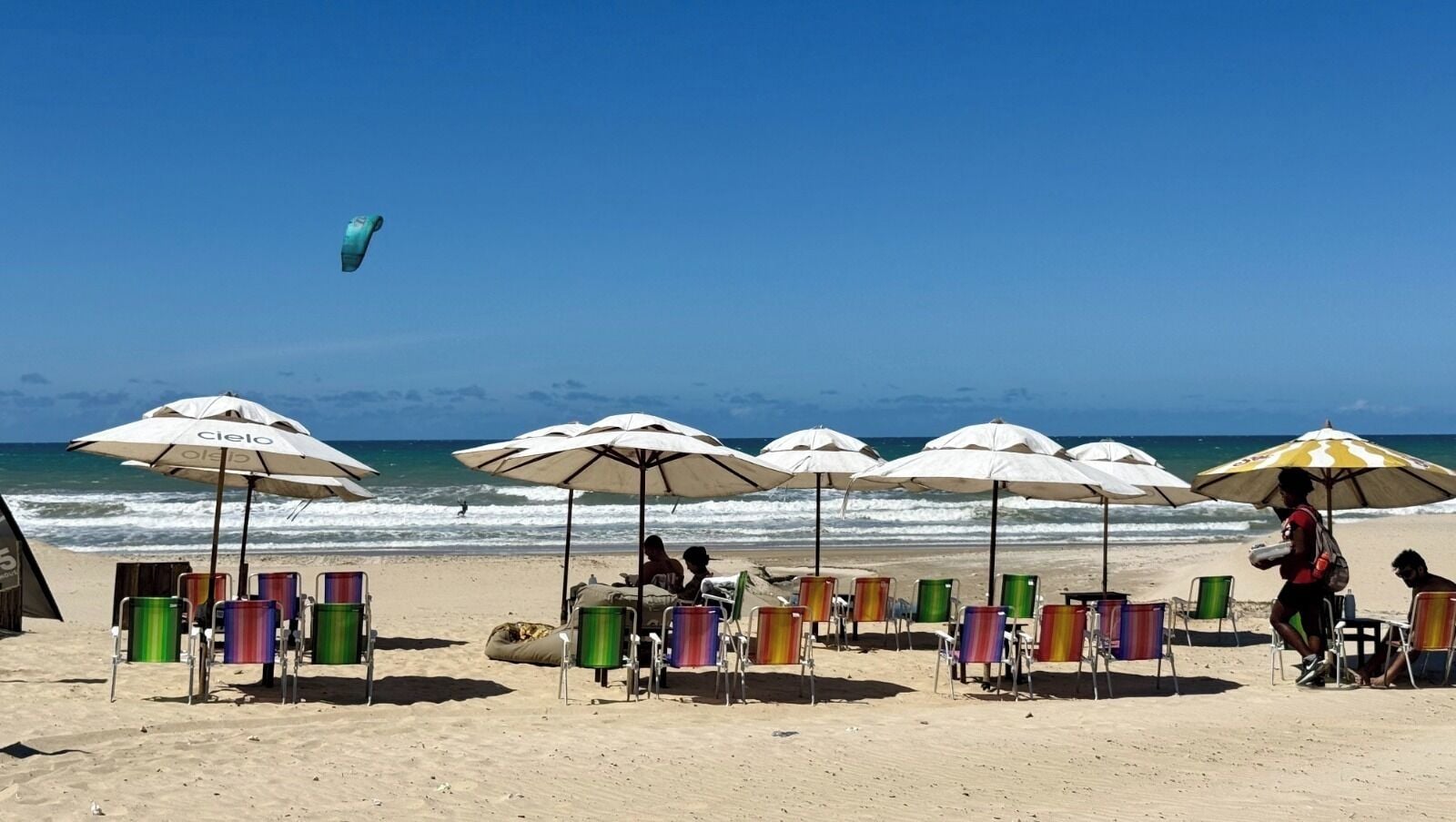 A beach with umbrellas, beach chairs, and a person walking.
