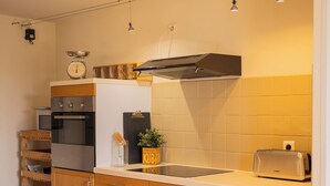 Kompakti keittiö, jossa on puukalusteet, sisäänrakennettu uuni, leivänpaahdin ja pieni pesuallas.