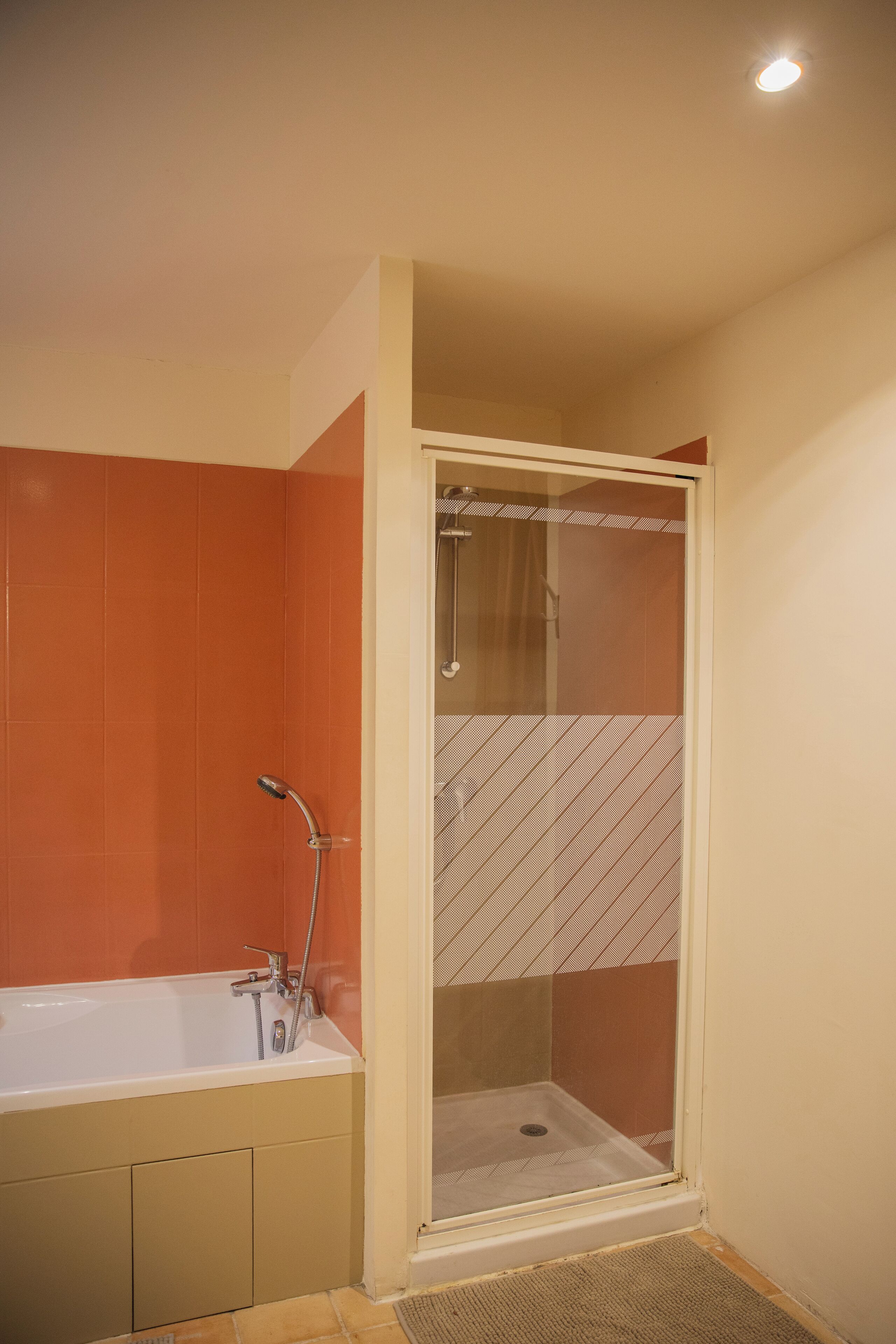 A bathroom with a bathtub, shower, and a glass-enclosed shower stall.