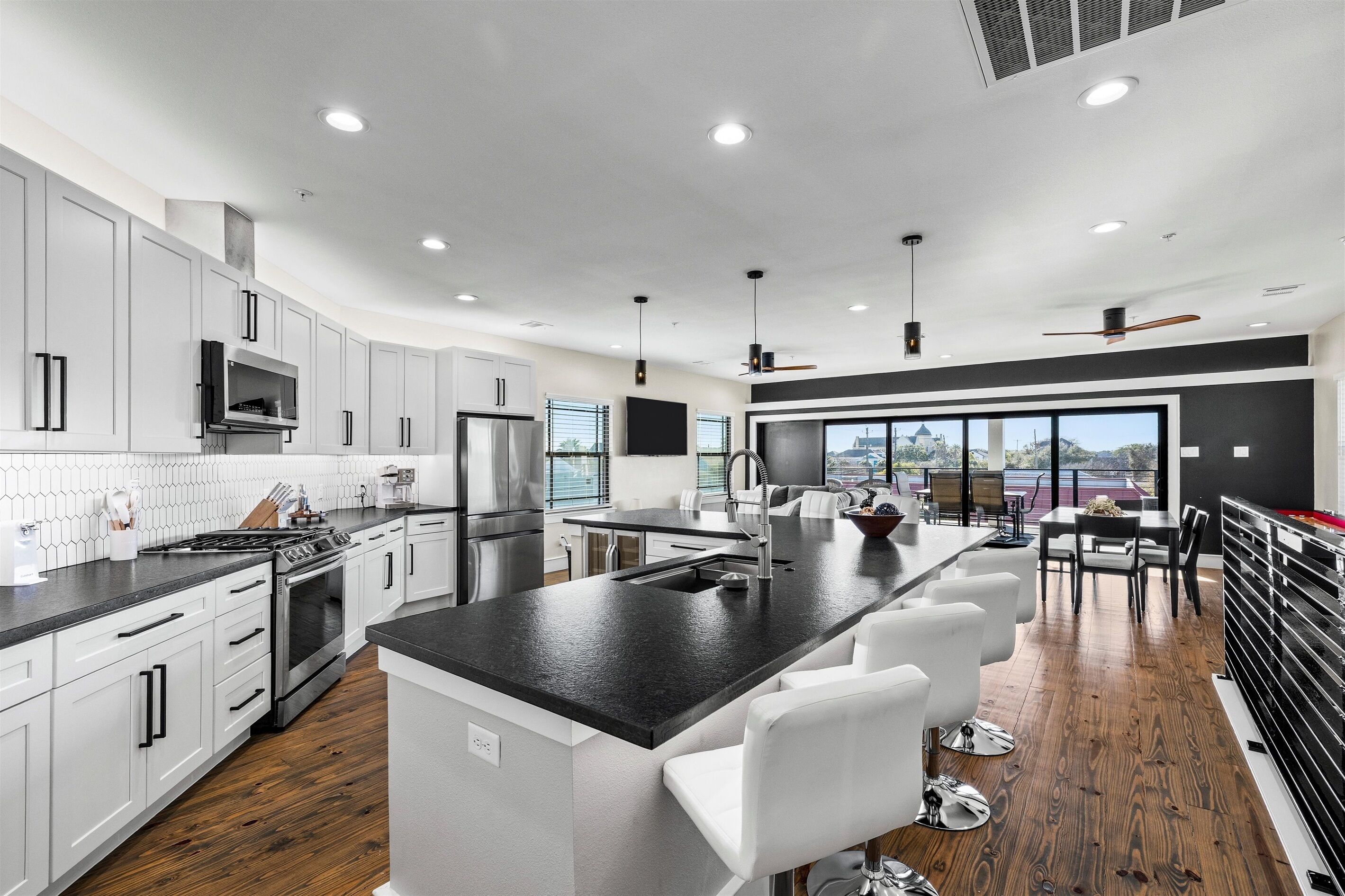 Una cocina moderna con armarios blancos, una isla central y un comedor con vistas.