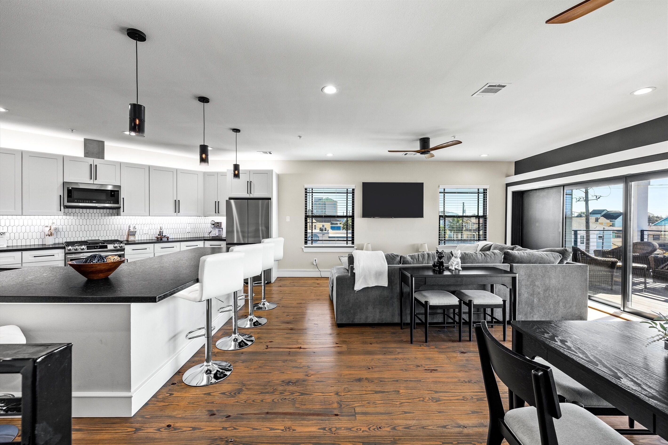 Una cocina moderna con una isla central, taburetes de bar y un comedor con mesa y sillas.