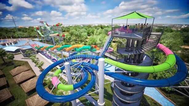 A water park with a multi-level water slide structure, a pool, and surrounding greenery. - Lux West End Retreat |Fire Pit, 210 Steps to Beach (Galveston)
