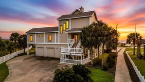 A two-story house with a covered porch, a garage, and a well-maintained lawn. - Lux West End Retreat |Fire Pit, 210 Steps to Beach (Galveston)