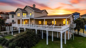 A two-story house with a balcony, a covered patio, and a view of the sunset. - Lux West End Retreat |Fire Pit, 210 Steps to Beach (Galveston)