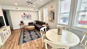 A modern living room with a sofa, a round dining table, and a ceiling fan. - 7 mins walk to Boardwalk & Beach! AC & Beach Tags! (Ventnor City)