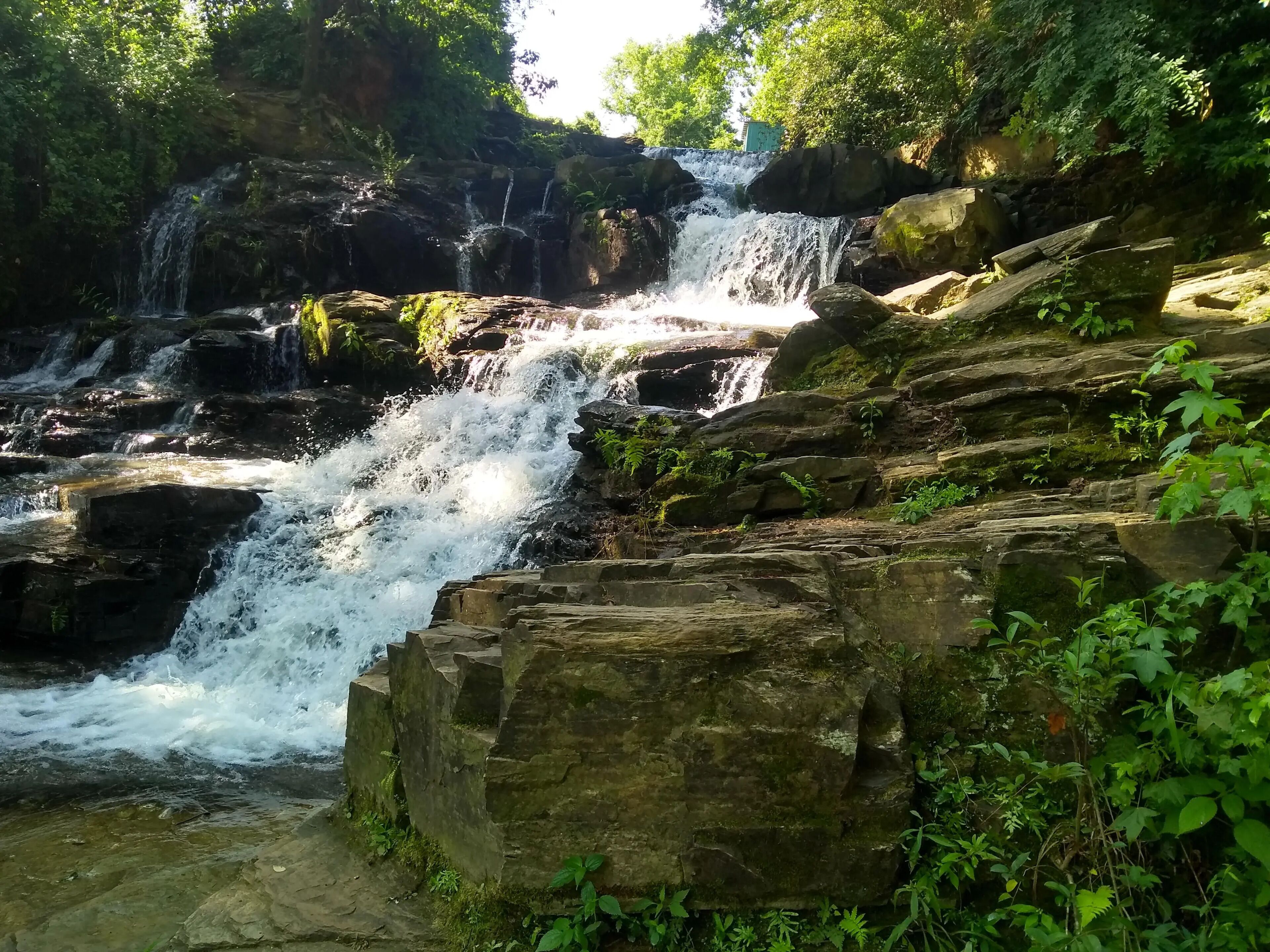A waterfall cascading over rocky terrain with lush greenery around.
