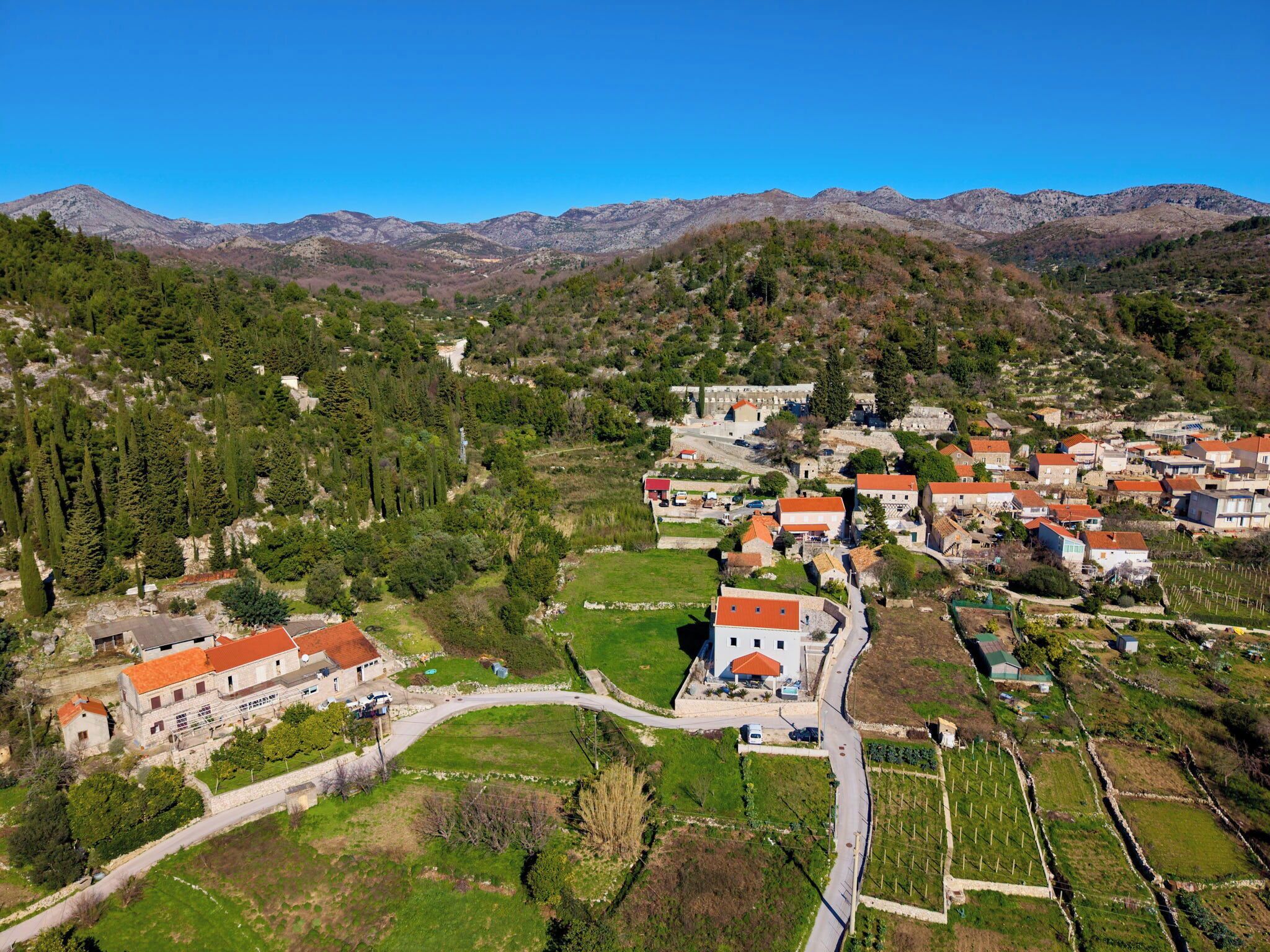 Vista aérea de un pueblo con casas, caminos y montañas circundantes.