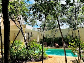 A pool surrounded by trees and plants, with a building in the background. - Penthouse S6 Private Pool Private Jacuzzi (Tulum)