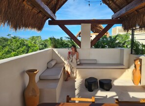 A rooftop terrace with a thatched roof, a cushioned seating area, and a table with chairs. - Penthouse S6 Private Pool Private Jacuzzi (Tulum)