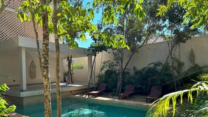 Un área de piscina con sillones de descanso y una pérgola.