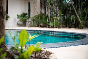 A swimming pool surrounded by tropical plants and a building in the background. - Tulum 2BR Penthouse Pool Rooftop gym B5 (Tulum)