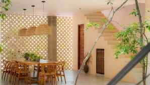A dining area with a wooden table and chairs, a woven pendant light, and a lattice partition. - Tulum 2BR Penthouse Pool Rooftop gym B5 (Tulum)