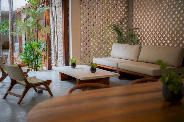 A cozy indoor seating area with a sofa and chairs, a coffee table, and potted plants. - Tropical Studio Pool Gym C6 (Tulum)