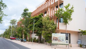 Un hotel moderno con diseño minimalista, que destaca un letrero llamativo y un jardín bien cuidado.