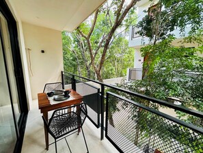 A balcony with a wooden table and chairs, surrounded by a black metal railing. - Jungle View Studio S19 Private Balcony Hammock Pool (Tulum)