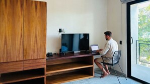 A modern room with a wooden cabinet, a flat-screen TV, a laptop, and a chair. - Pool Peaceful Escape Cozy Jungle Studio S12 (Tulum)