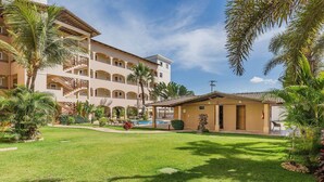 A hotel with a pool, palm trees, and a well-maintained lawn. - Cumbuco Residence #309 - 2 Bedrooms by Carpediem (Caucaia)