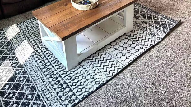 Un salón con dos sofás de cuero marrón, una mesa de centro de madera con una cesta trenzada y alfombras estampadas.
