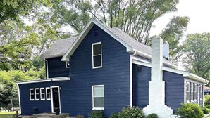 Una casa de dos pisos con fachada azul oscuro, una chimenea y un pequeño porche.