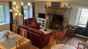 Un salon avec une cheminée, un ensemble de canapés, une table à manger et un téléviseur.