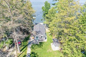 Une maison avec un toit en pente, entourée d’arbres et dotée d’une petite cour.